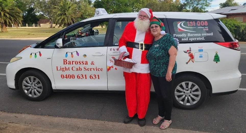 Santa and elf delivering Christmas gifts to local hospital patients